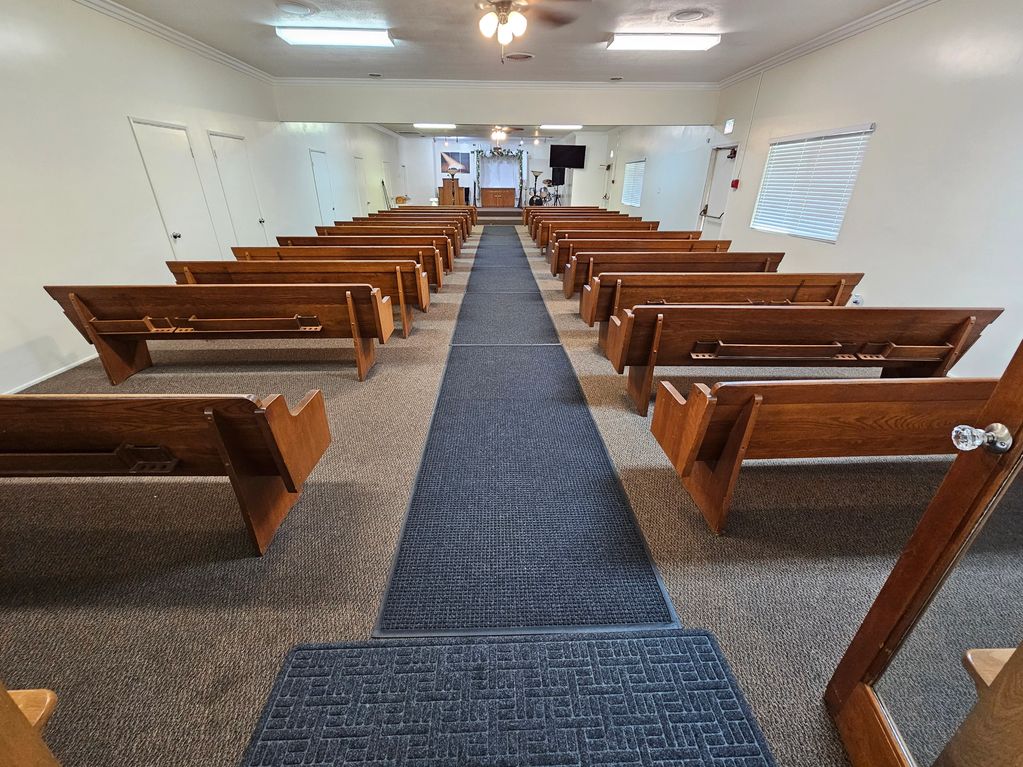 Empty church interior with wooden pews and a central aisle leading to the altar.