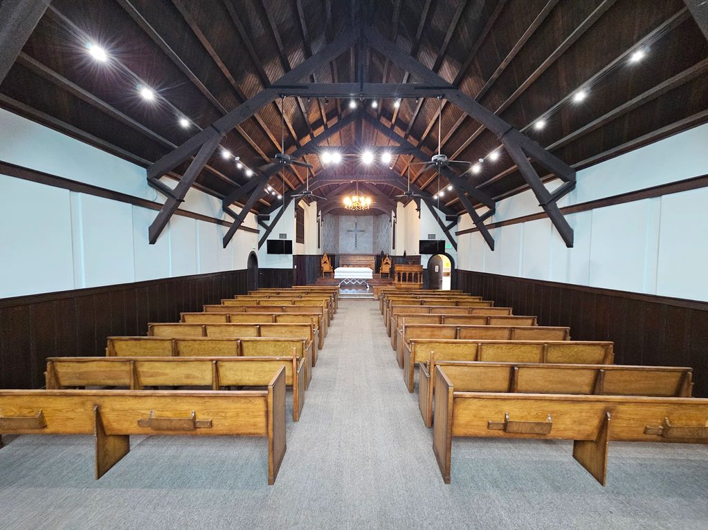 Interior of a small chapel with wooden pews and a high arched ceiling.