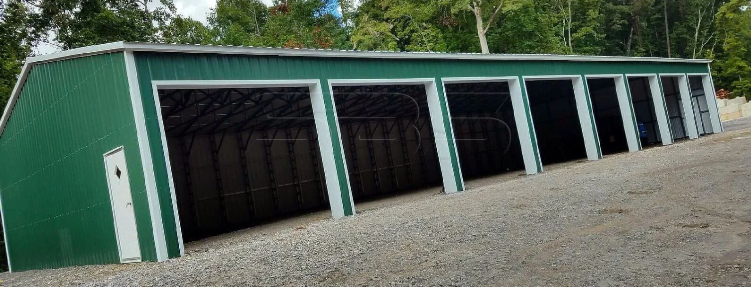 Green metal building with multiple open garage doors.