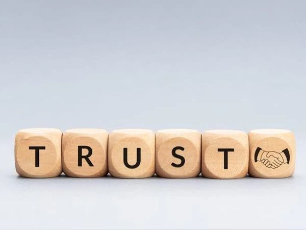 Wooden blocks spelling 'TRUST' with a handshake symbol.