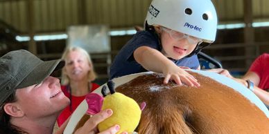 Young rider working with volunteer on core strength and flexibility.