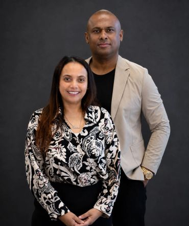 Portrait of a smiling couple against a dark background.