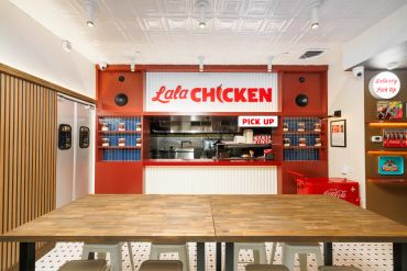 Modern chicken restaurant counter with pick-up window and wooden table.