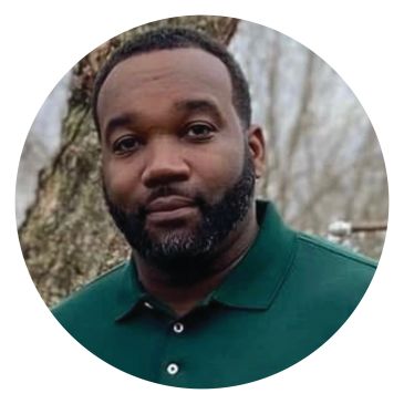 Man with beard in a green shirt outdoors.