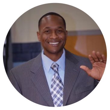 Smiling man in a suit waving.
