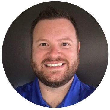 Smiling man with beard in blue shirt.