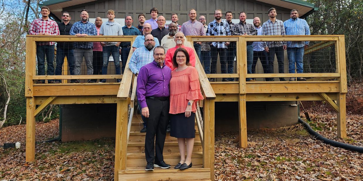 A group of people posing on a wooden deck and stairs outdoors.