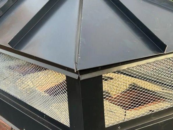 A black chimney cap on a brick chimney to protect it.