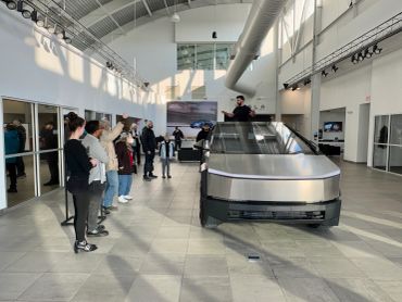 Group touring Tesla Cybertruck inside showroom.