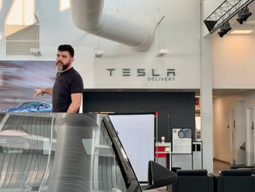 Man gestures inside Tesla delivery center.