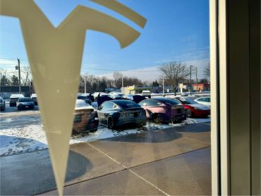 Two Tesla cars charging outside on a snowy day.