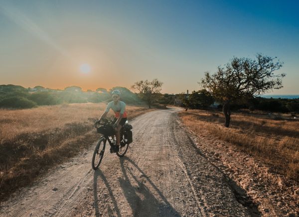Fahrradfahrer bei Sonnenuntergang auf einem ländlichen Weg.
