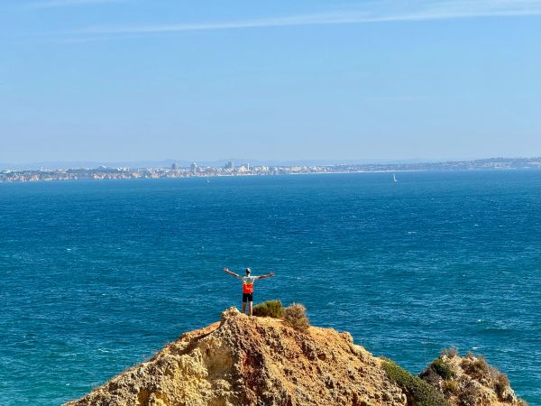 Person steht auf einem Felsen mit Blick aufs Meer.