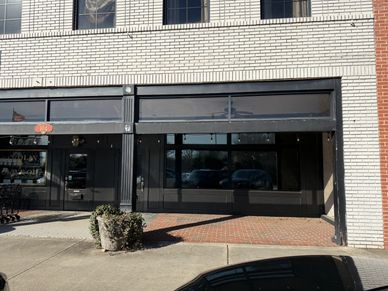 Empty storefront with large windows and black framing.