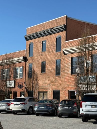 Brick office building with parked cars on a sunny day.