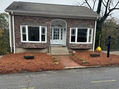 Small stone house with new mulch in front yard.