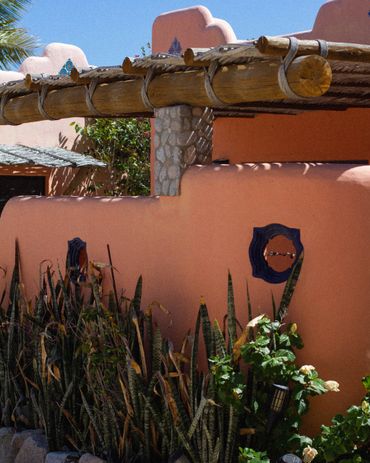 Rustic adobe-style building with wooden beams and desert plants.