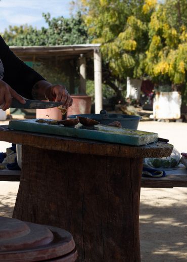 Person chopping food outdoors on a rustic wooden table.