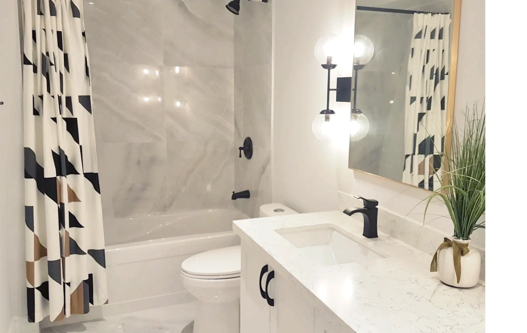 black and white bathroom with onyx style porcelain tiles. wall mounted sconces, double sink vanity.