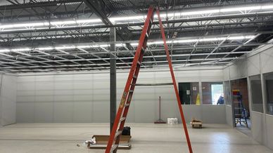 A large room under construction. There's a ladder in the middle of the room.