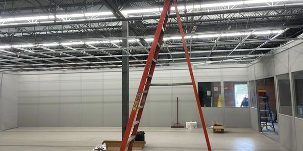 An interior view of a modular wall system under construction in a warehouse with an orange ladder l
