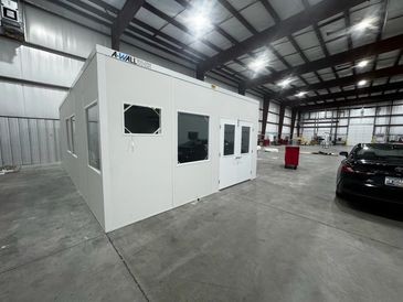 A modular cleanroom structure stands in a large warehouse, ready for installation inside a warehouse