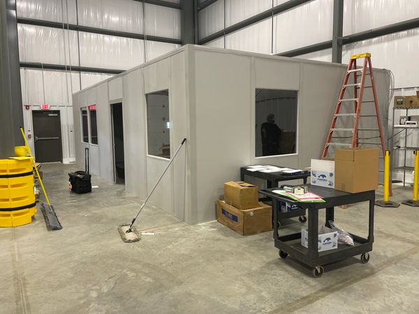 A large grey modular installations designs of SoFlo, with several windows, door, inside a warehouse 