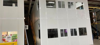 A white two story modular office building inside an industrial setting & built by SoFlo Installation
