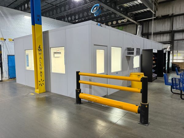 A white modular office installation with windows and a door, labeled 'A-WALL building systems