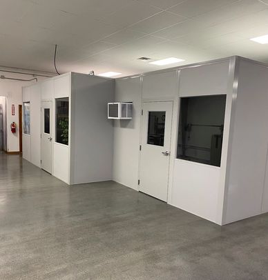An inPlant modular grey building inside an office space, with several windows and doors and AC units