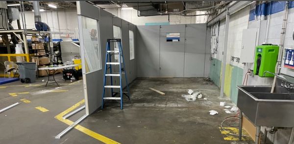 A grey modular office installation being constructed off an existing wall, with several windows