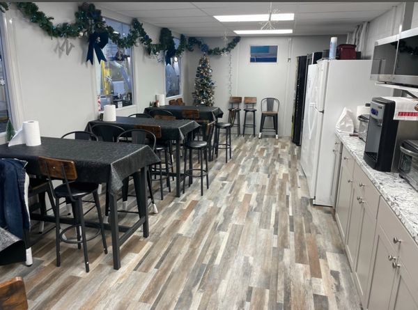 A long, narrow modular installation break-room building with a light wood-look floor and white walls