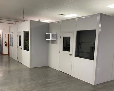 A new grey modular office expansion of an existing prefab building with several windows, AC, & doors