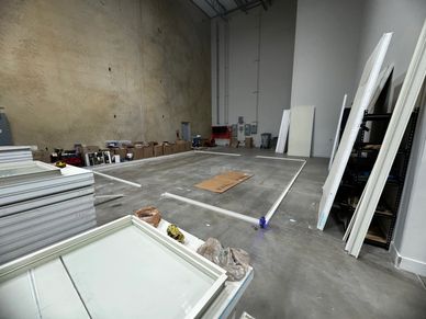 An empty warehouse space with materials laid out on the concrete floor for the construction of a mod