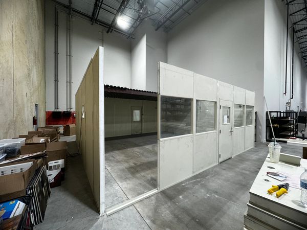 A modular office being constructed with several windows, a door and only missing the last panel.