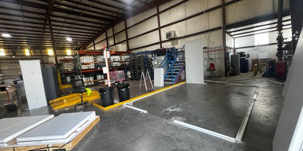 A warehouse interior during the construction of modular offices. Wall panels and door frames lean ag
