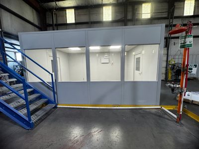 A prefabricated modular office with large windows in an industrial setting.