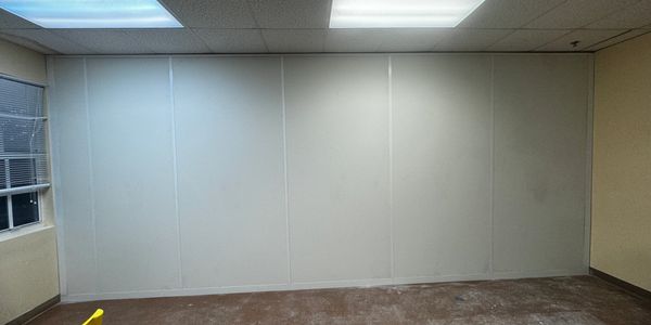 A white, floor-to-ceiling room divider or partition wall in an office space. 
