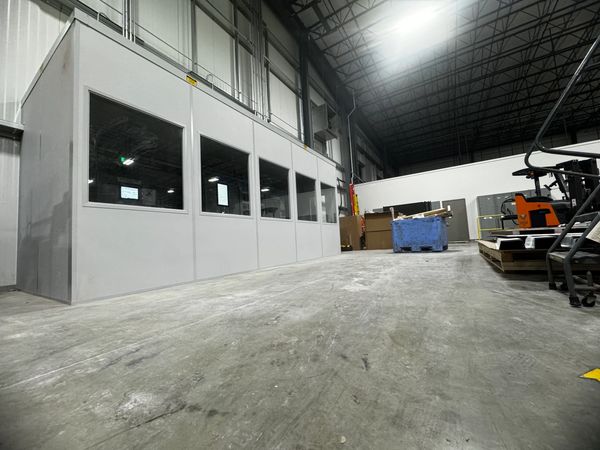 A modular in-plant office with large windows installed inside a warehouse.