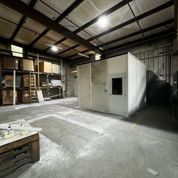 A prefabricated modular office unit stands inside a large warehouse. With a door with glass.