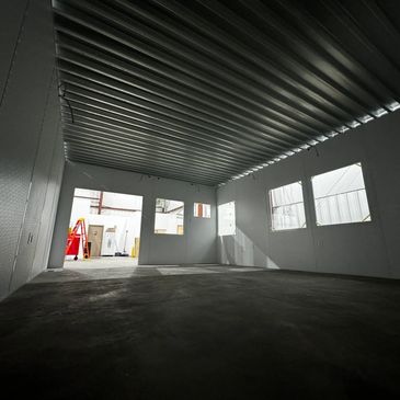 A spacious, prefabricated modular office interior with white walls, large windows, & roof deck.