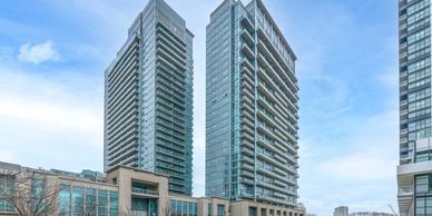 Two modern high-rise glass buildings under a partly cloudy sky.