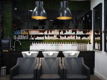 Modern hair salon washing station with three sinks and shelves of hair products.