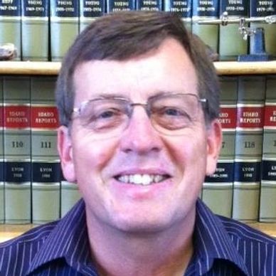 Man smiling with bookshelves in background.