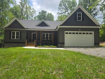 Dark gray house with white garage door, surrounded by greenery.
