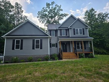 Two-story gray house surrounded by trees.