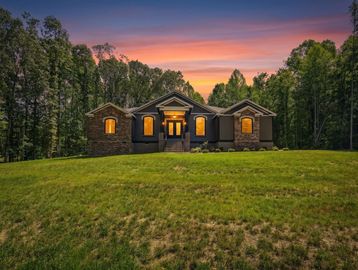 House glowing warmly at sunset surrounded by trees.
