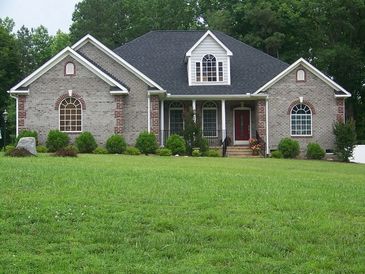 Brick house with a black roof and green lawn.
