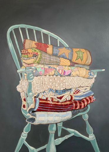 A windsor chair full of folded quilts