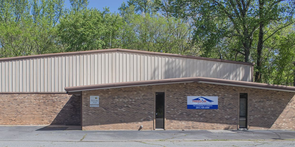Brick and metal commercial building with two business signs and trees in the background.